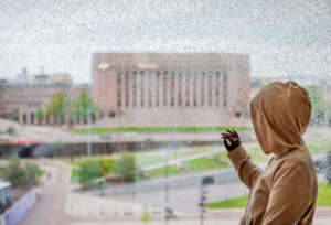 Nuori henkilö katsoo Eduskuntataloa ikkunan läpi