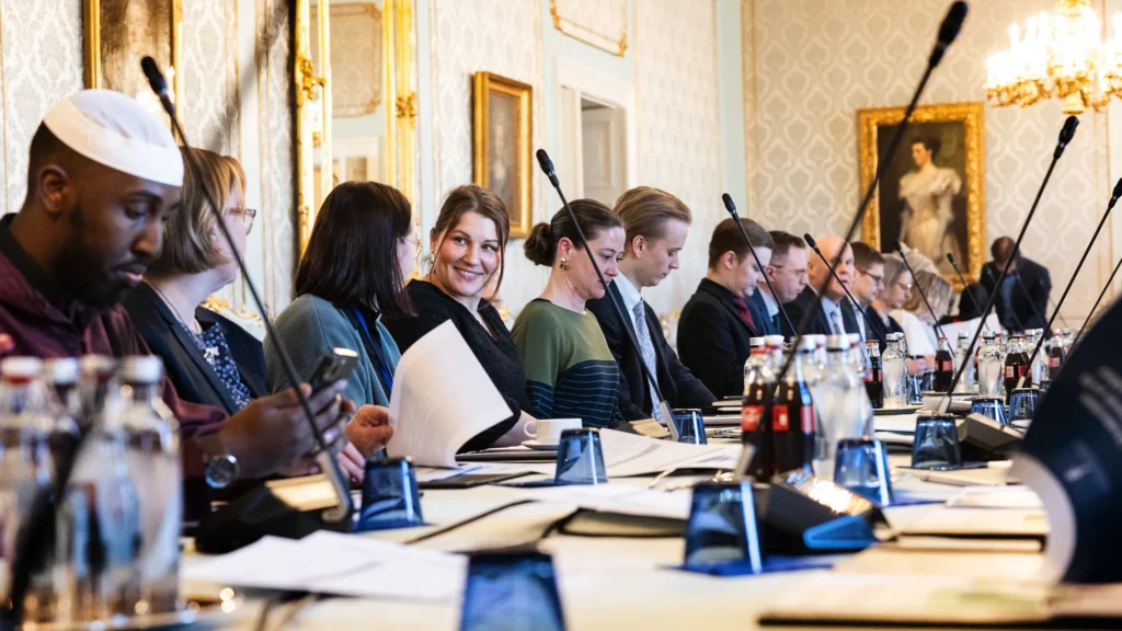 ryhmä maahanmuuttajataustaisia ihmisiä istuu kokouksessa valtioneuvoston kansliassa