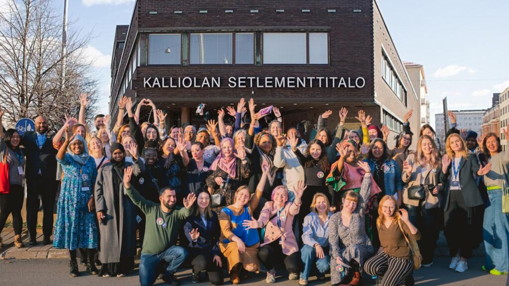 Suuri joukko iloisia ihmisiä rakennuksen edustalla.