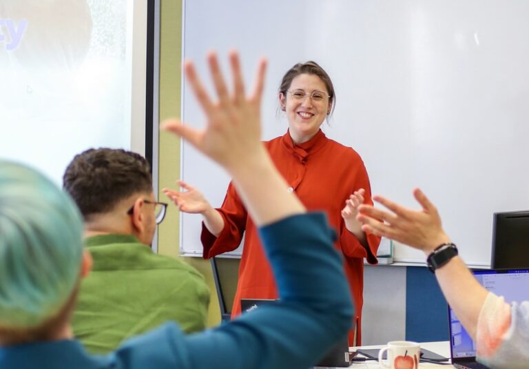 Julie Breton teaching and smiling in front of a whiteboard